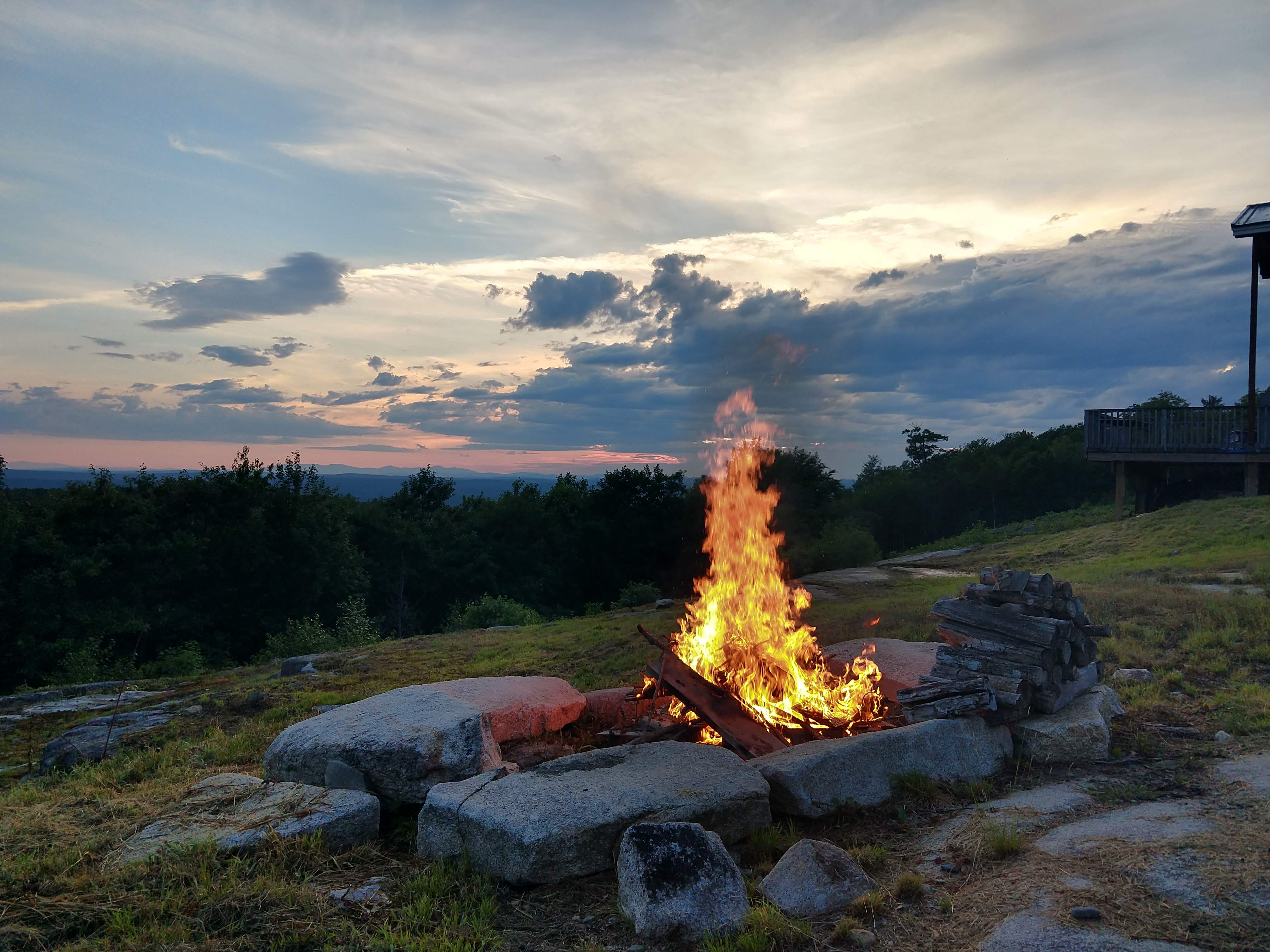 Evening fire pit on the granite ledge with the deck of the home in view
