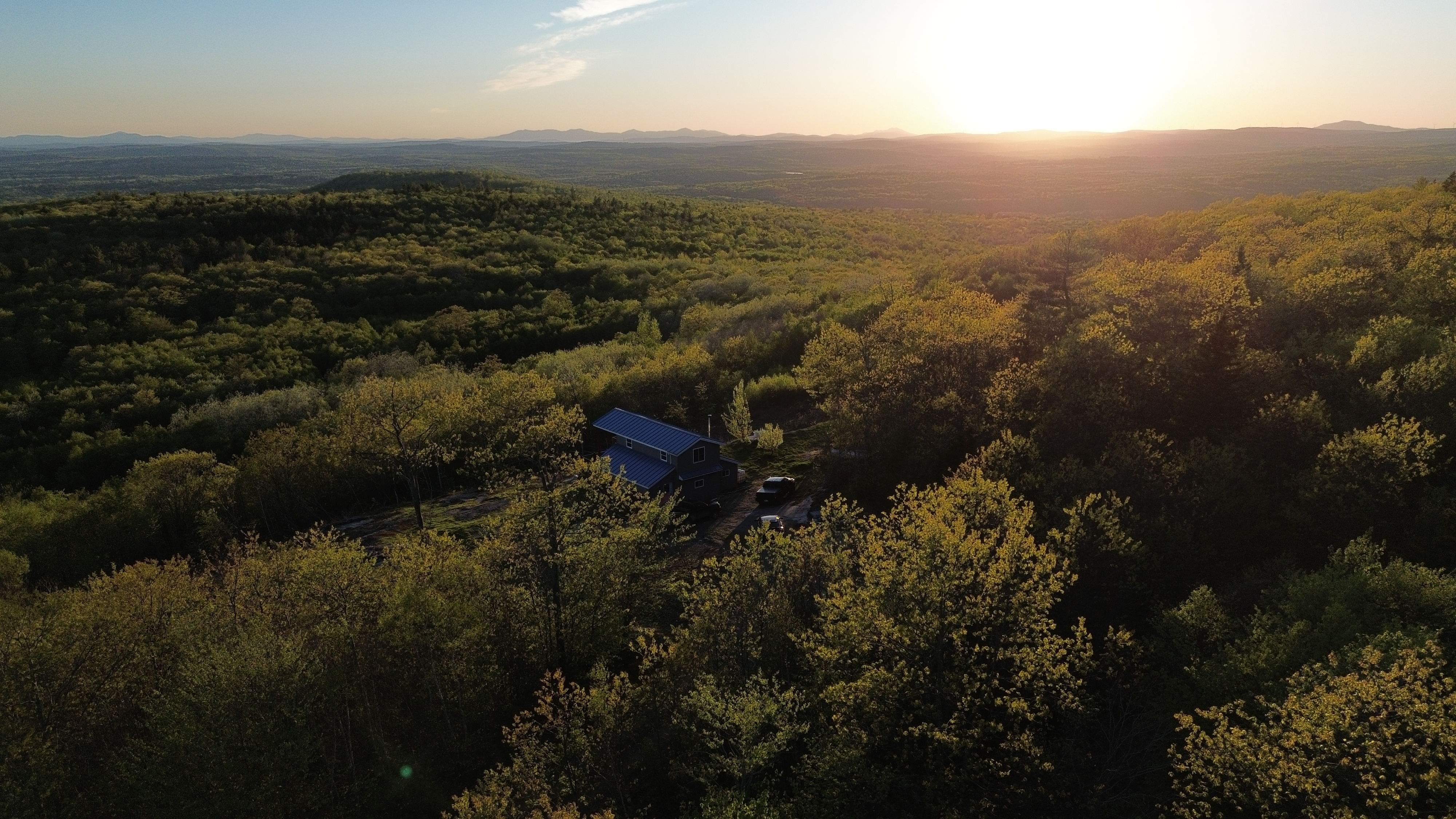 Aerial view of the home set in unbroken woodland at sunset