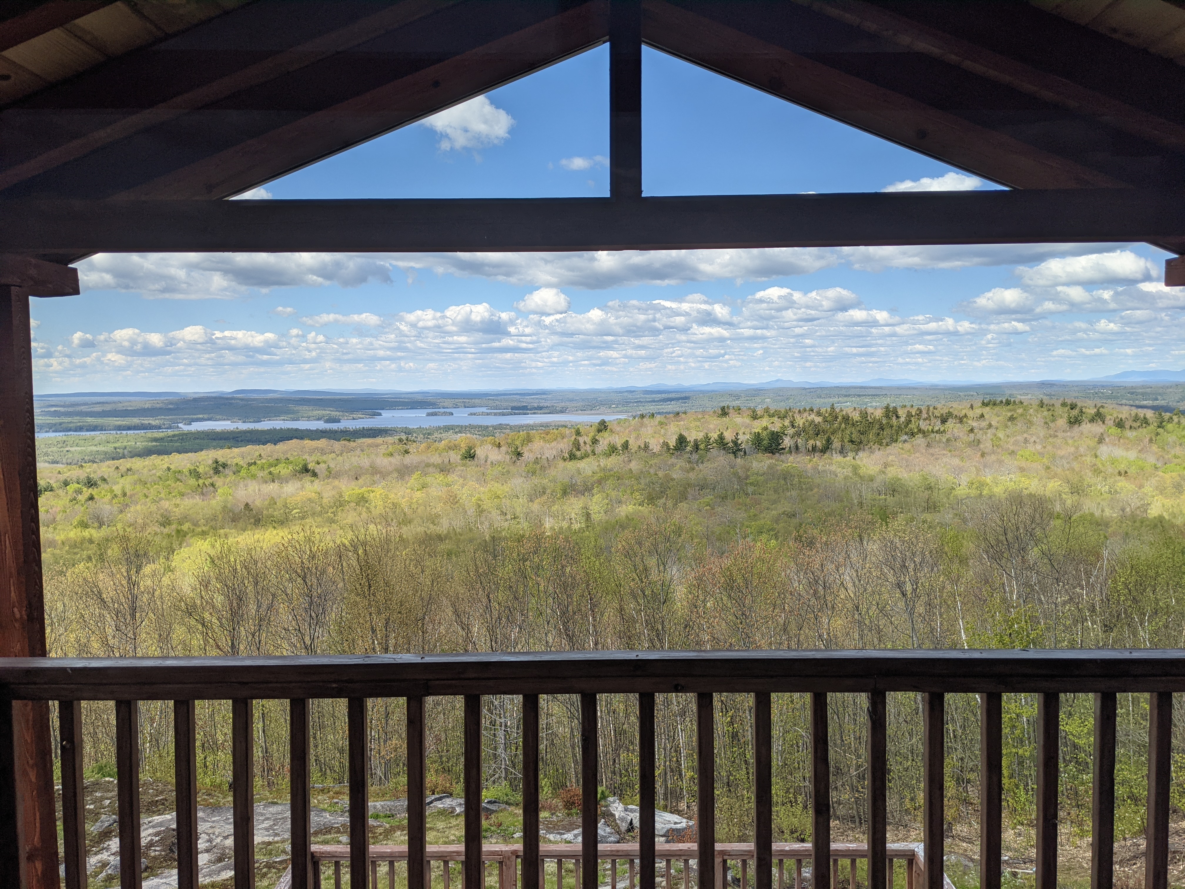 Spring lake view framed by the deck pergola, with hills beyond